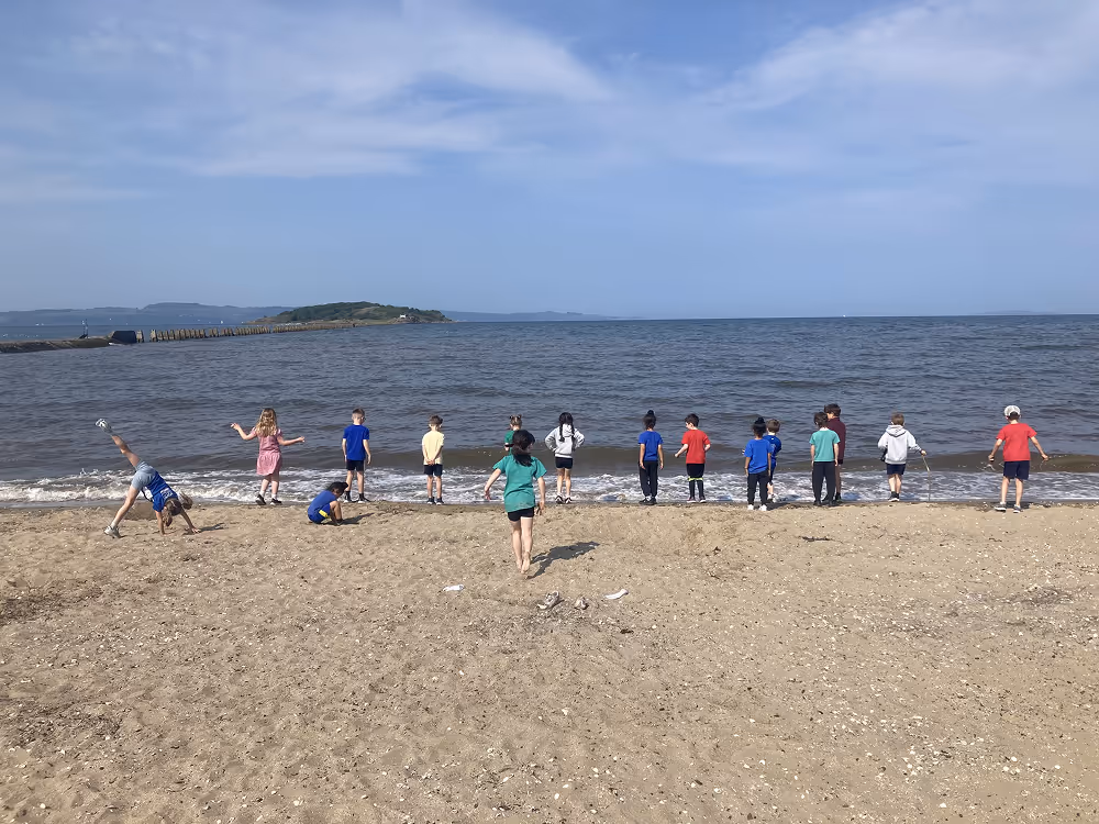 kids running at the beach with the sea in background