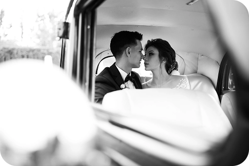 Bride and groom sharing a kiss inside a vintage car, black and white image conveying classic romance and sophistication.