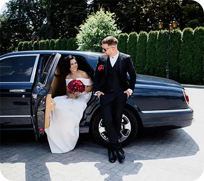 Bride stepping out of a luxury car while the groom waits beside her, showcasing refined arrival and chauffeur service elegance.