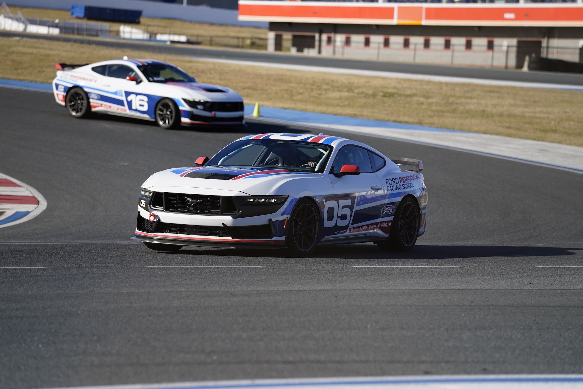 Close-up of a blue McLaren 750S sports car showing the side mirror, window, and front wheel with tire details.