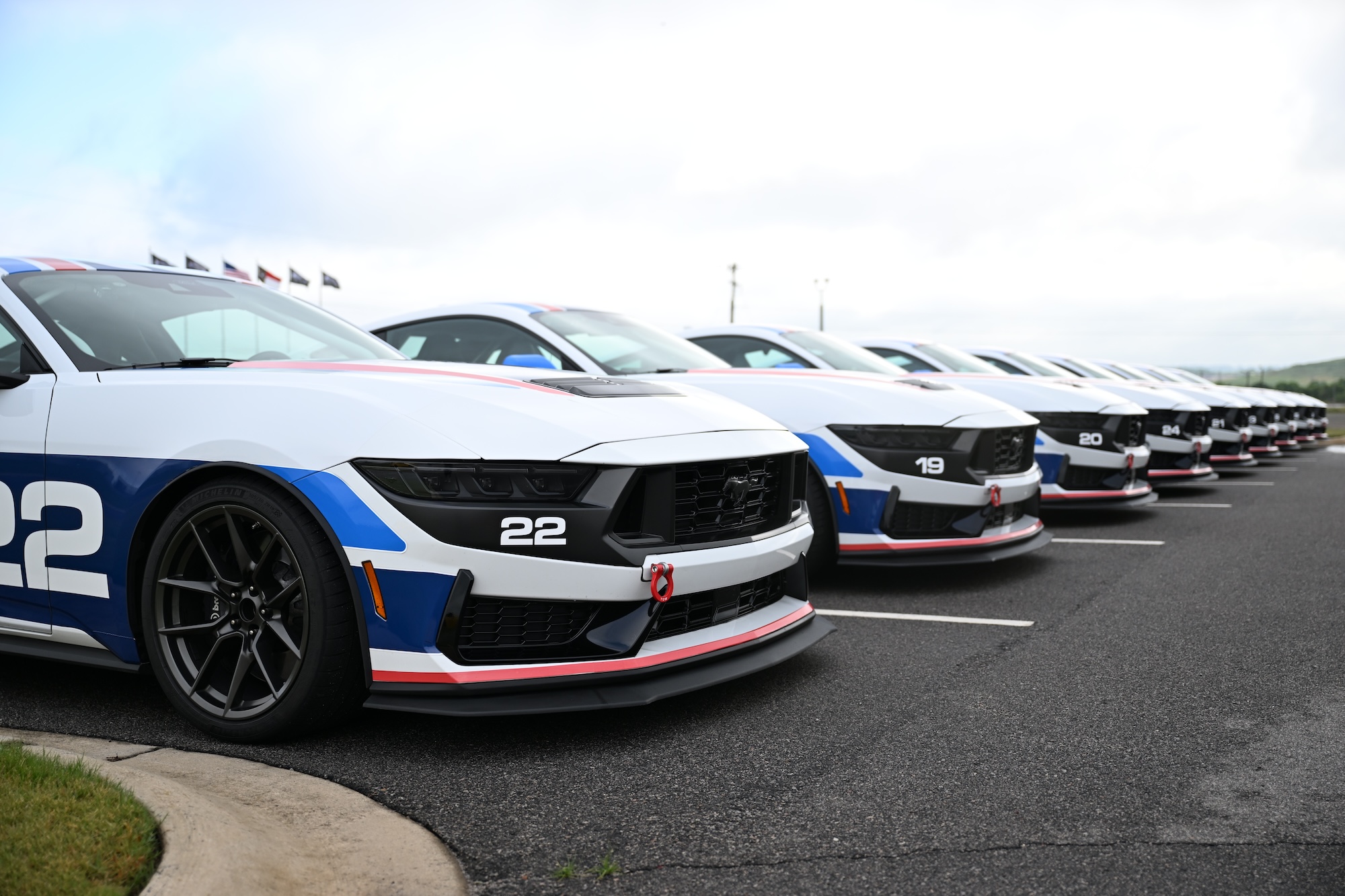 Close-up of a blue McLaren 750S sports car showing the side mirror, window, and front wheel with tire details.