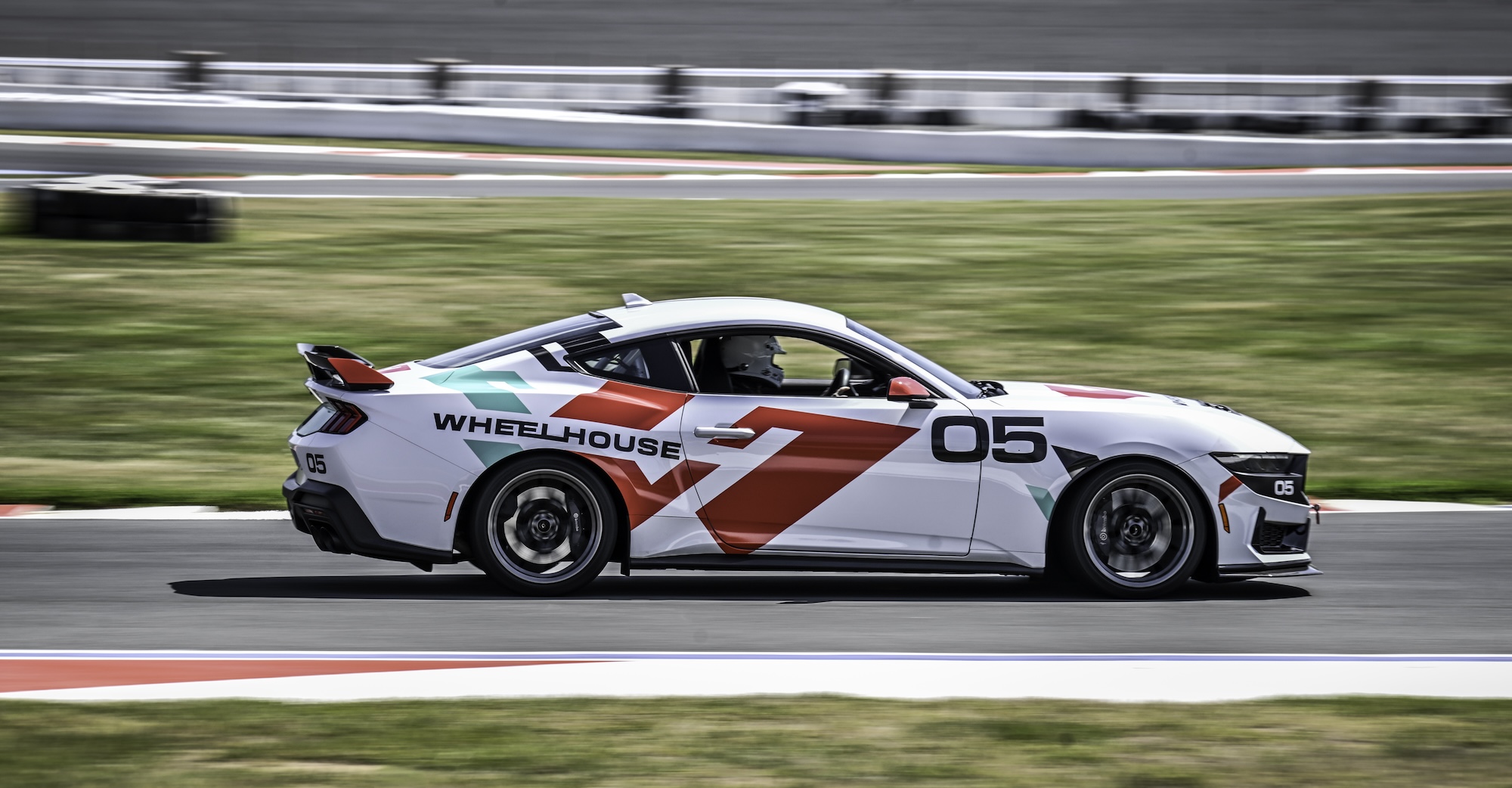 Close-up of a blue McLaren 750S sports car showing the side mirror, window, and front wheel with tire details.