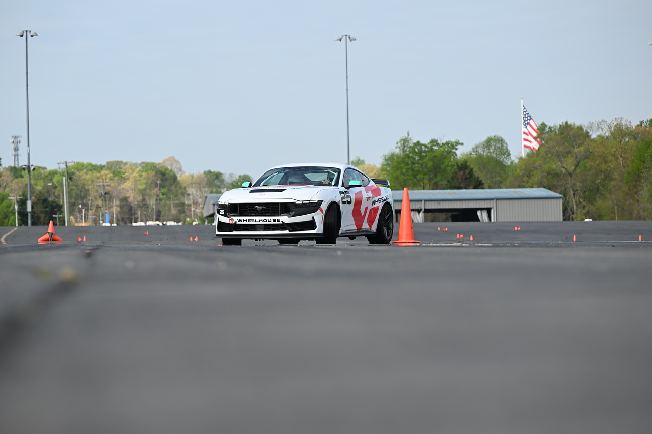 Close-up of a blue McLaren 750S sports car showing the side mirror, window, and front wheel with tire details.
