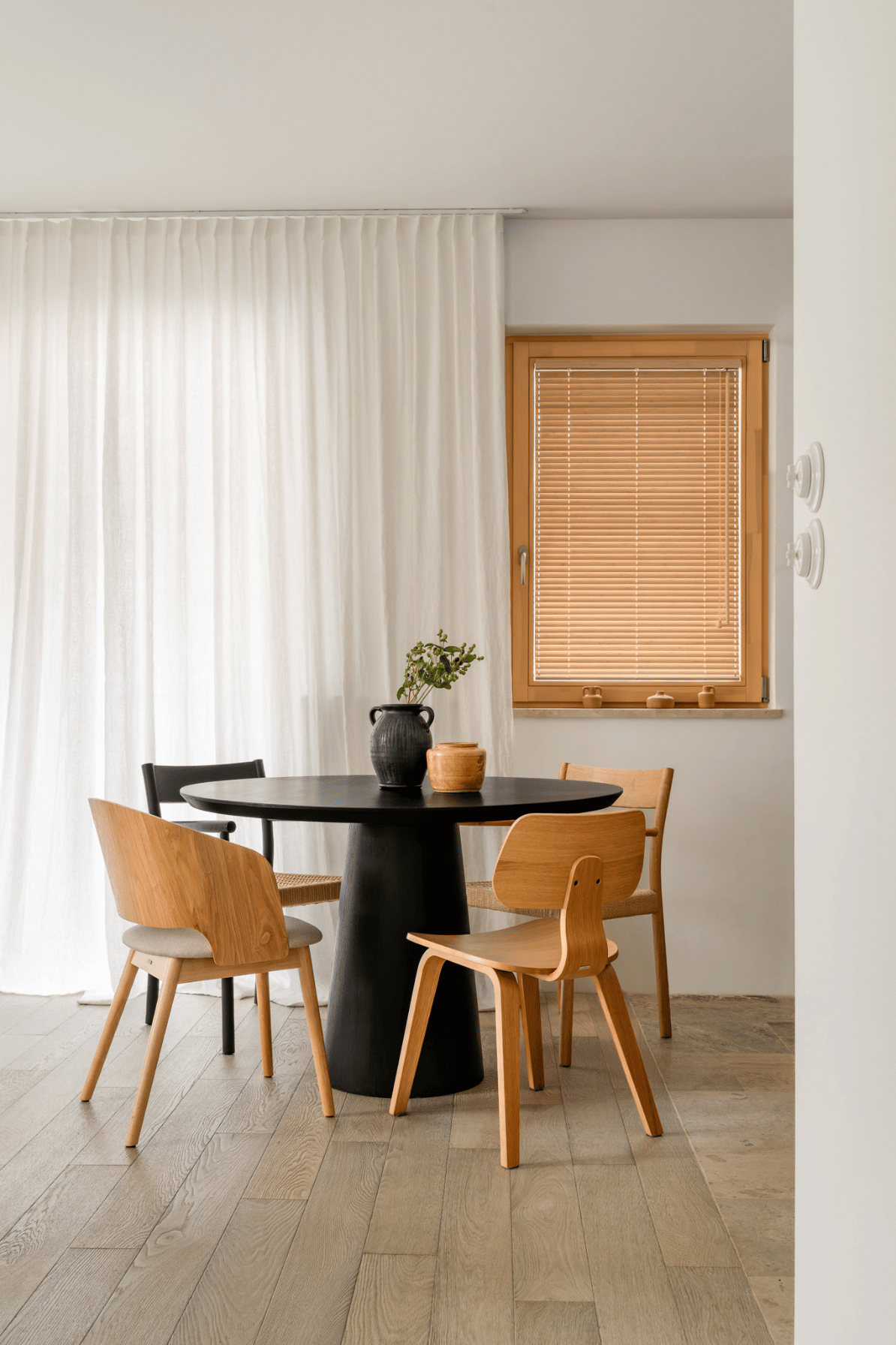 Round black wooden HOOM table on a central base with four chairs – an example of a table for four