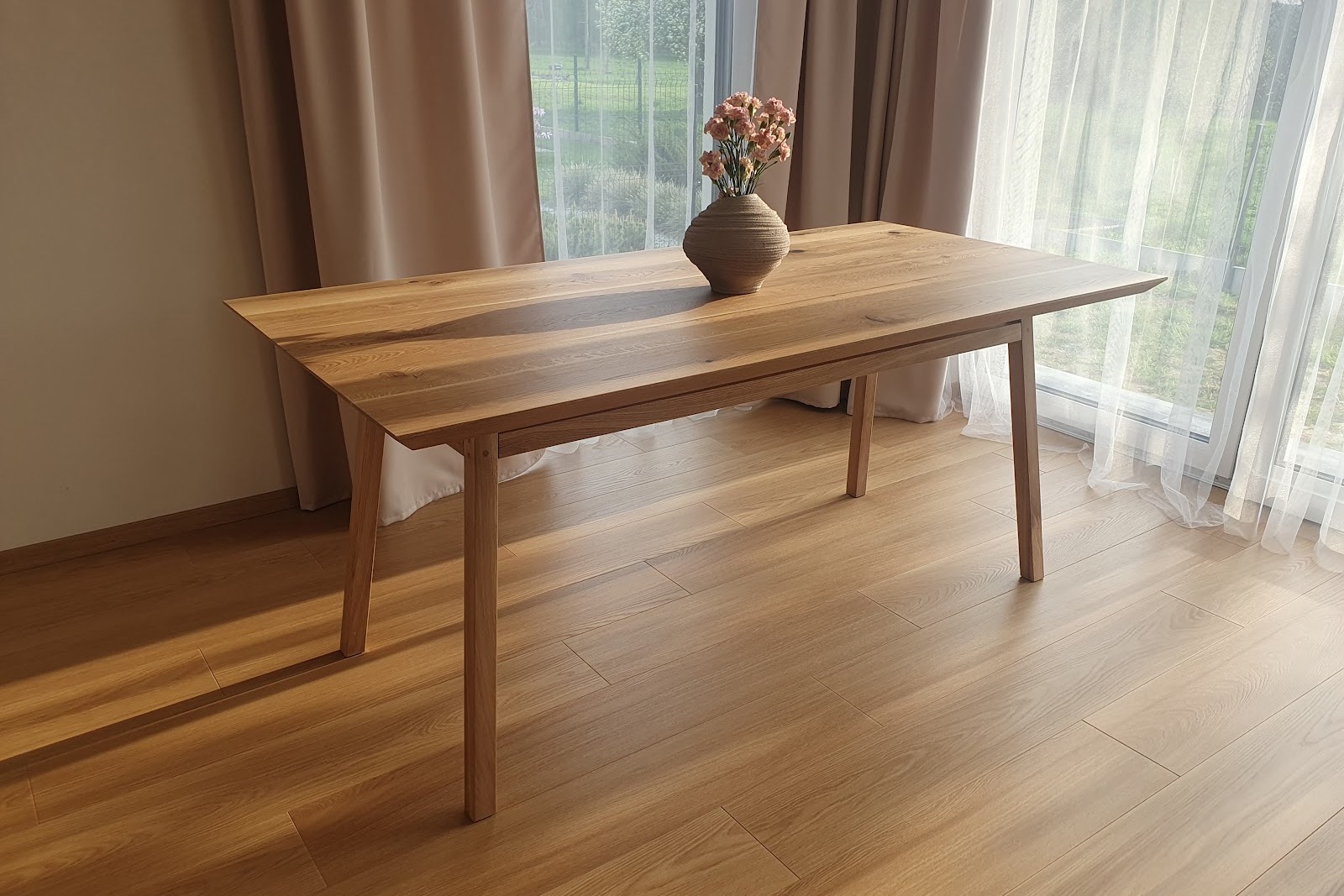Rozkładany stół George 180 × 90 cm ustawiony przy dużym oknie.