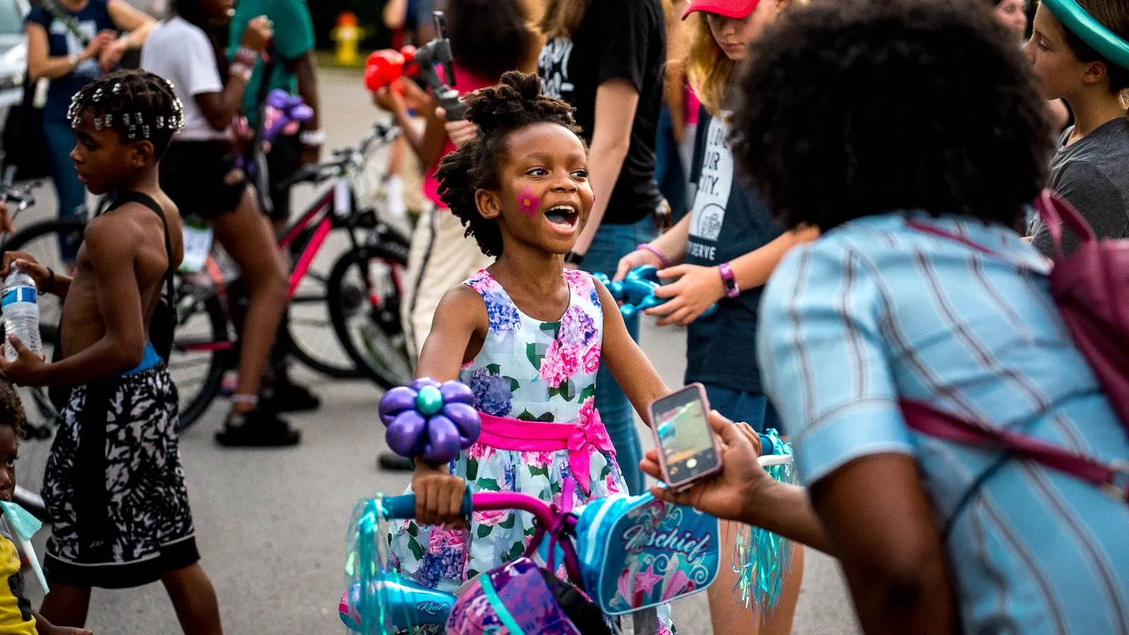A little girl riding a bike in a parade.