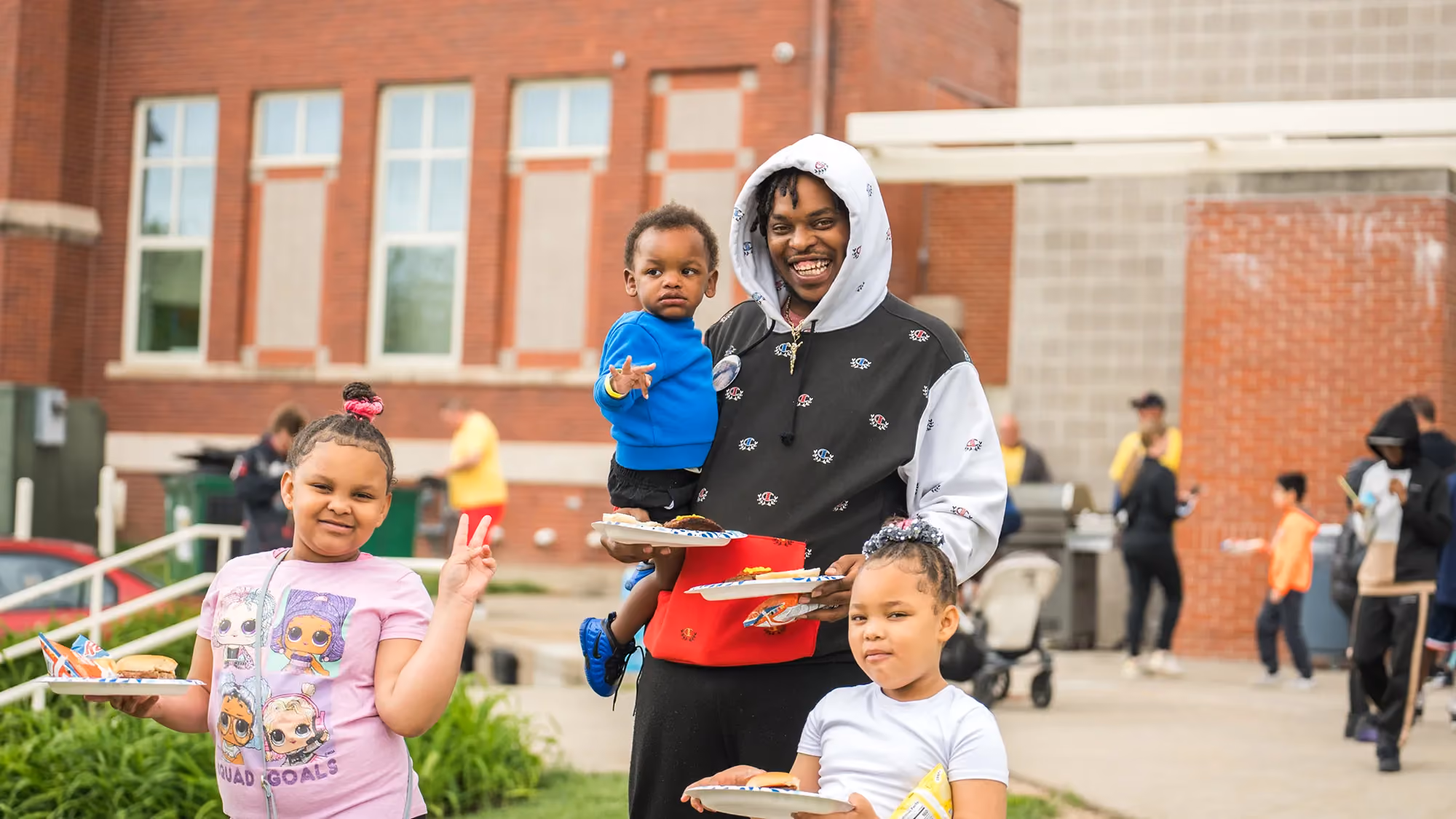 A man holding a tray of food while standing next to two children.