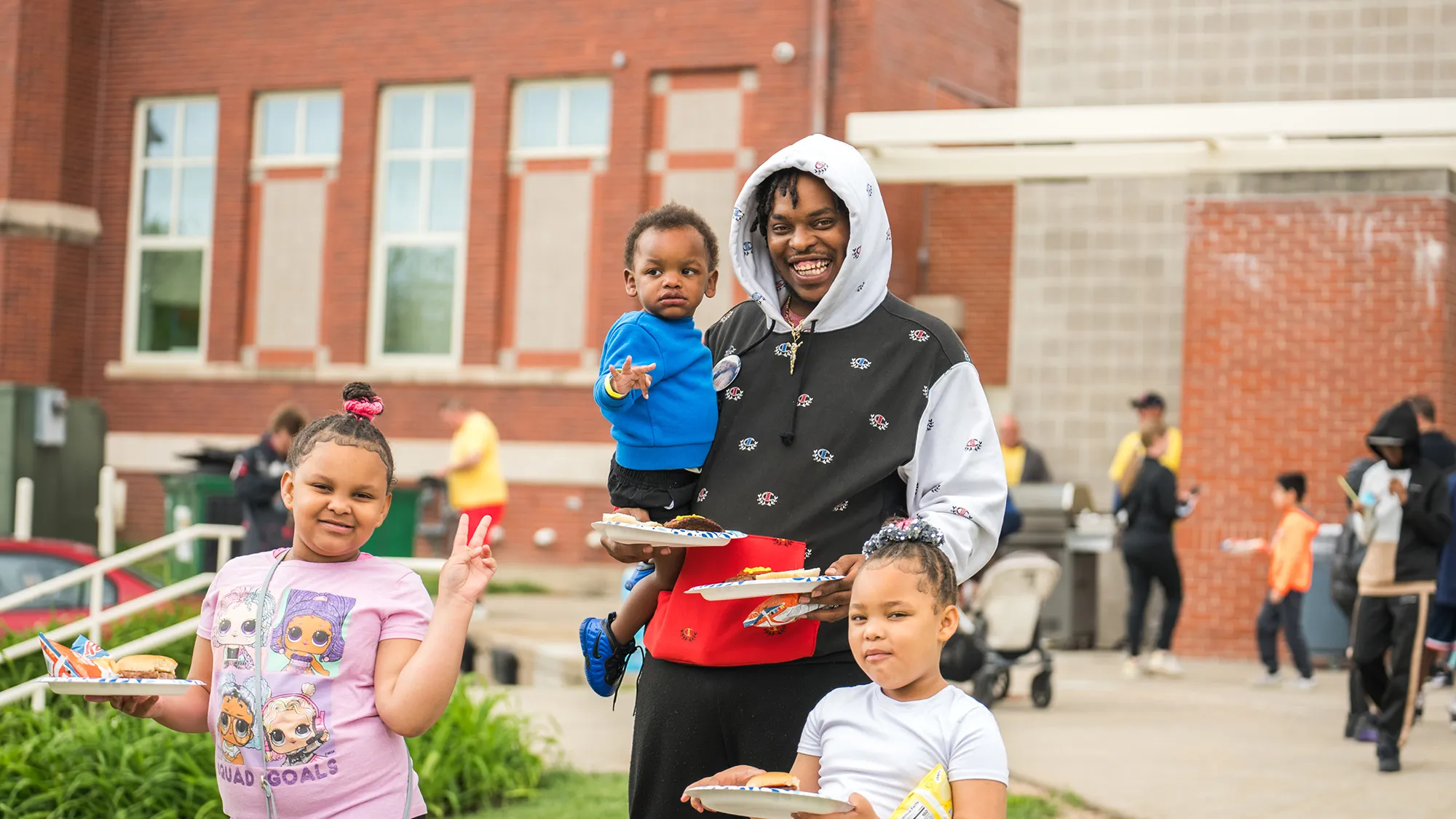 A man holding a tray of food while standing next to two children.