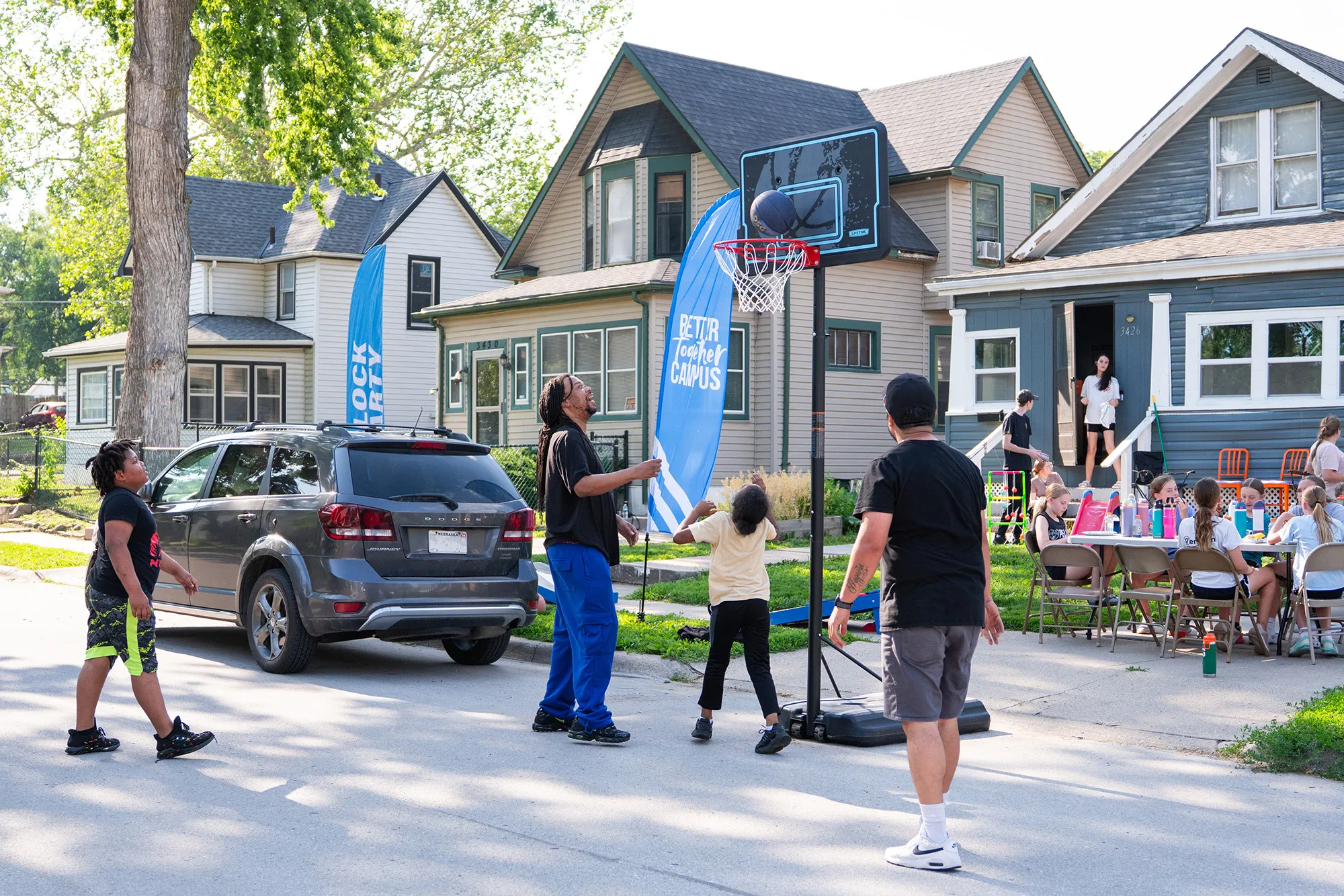 A group of people playing basketball in front of a house.