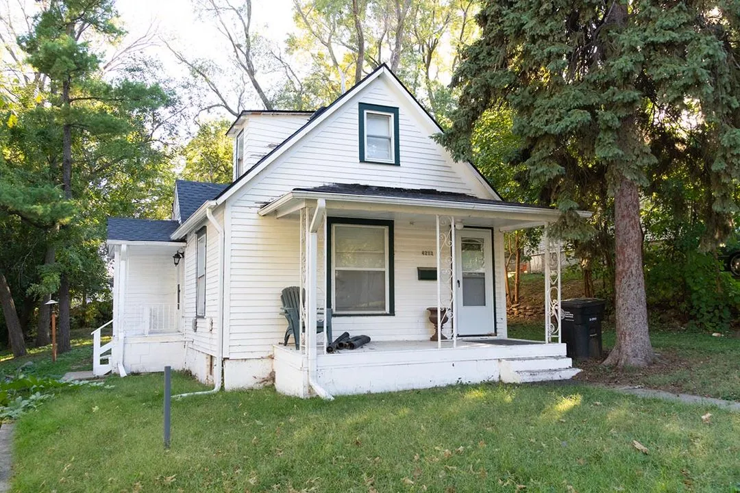 A small white house sitting in the middle of a yard.