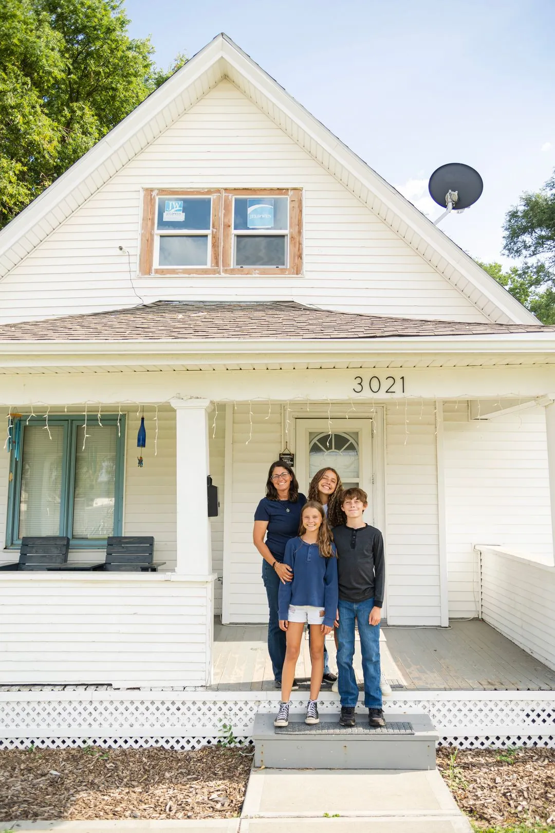 A family standing in front of a white house.