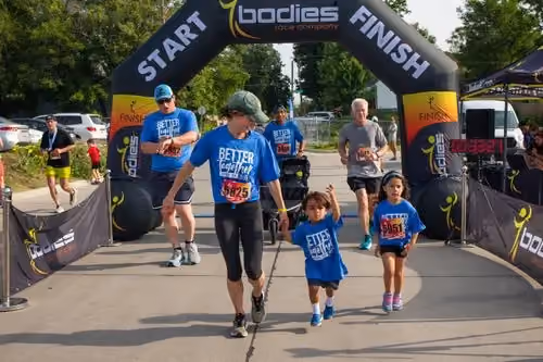 A family runs hand in hand across the Better Together 5K finish line.