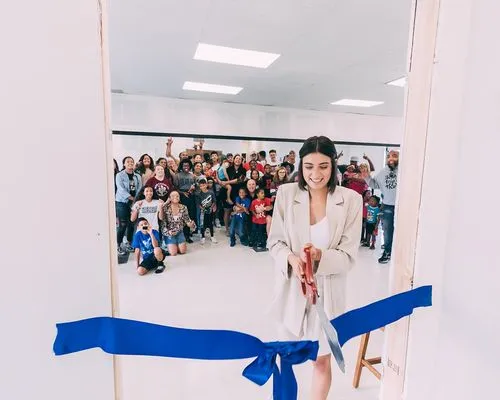 A woman holding a large pair of scissors in front of a crowd of people.