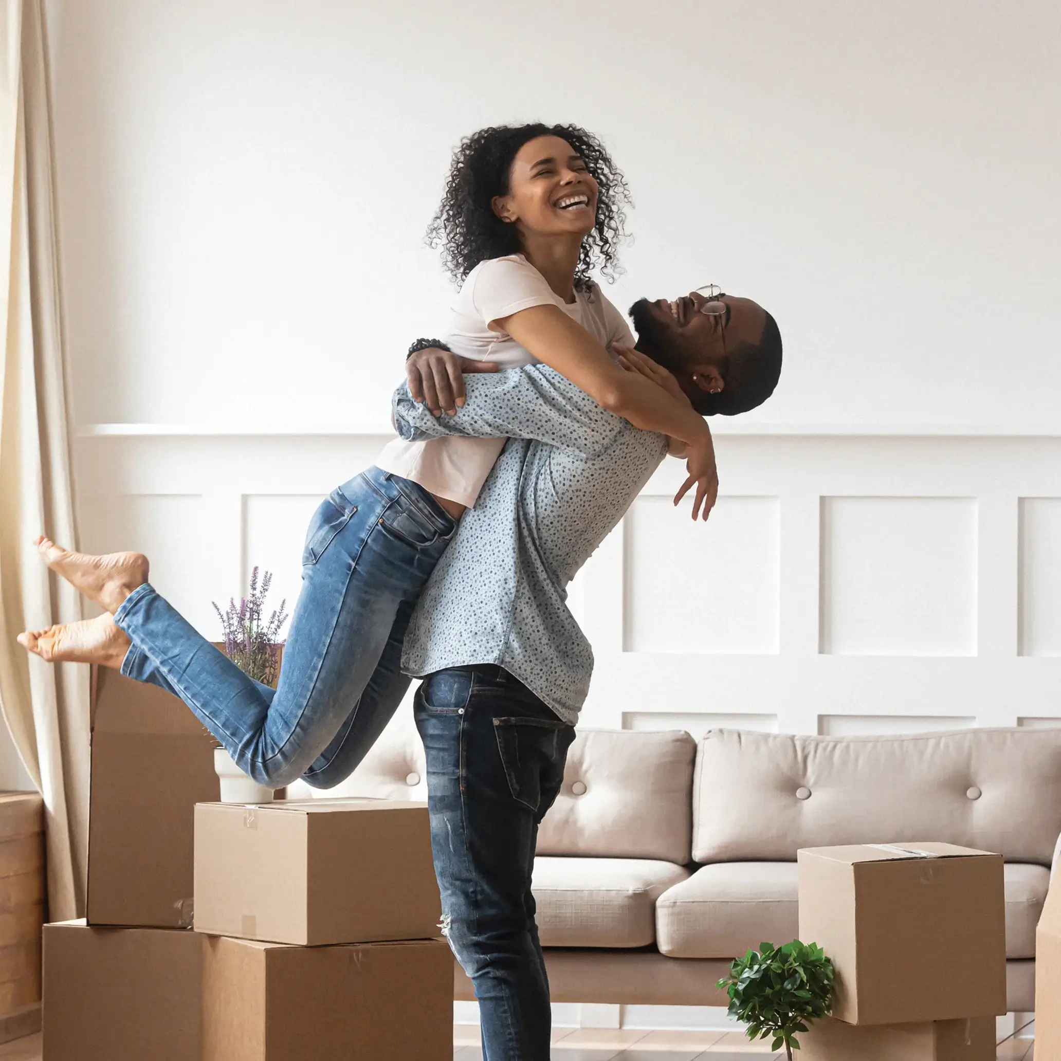 man picking up woman in a room with moving boxes