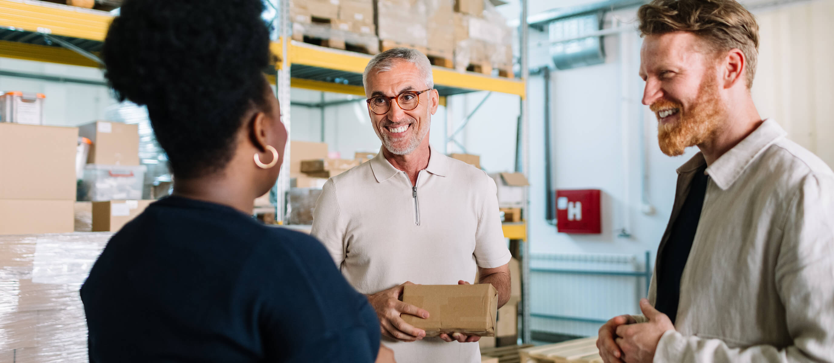 Woman and two men having a conversation in a warehouse