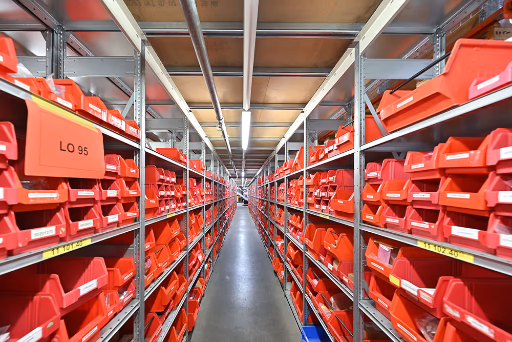 Lagerregale mit Reihen von roten Kunststoffbehältern in einem gut beleuchteten Lagerraum.