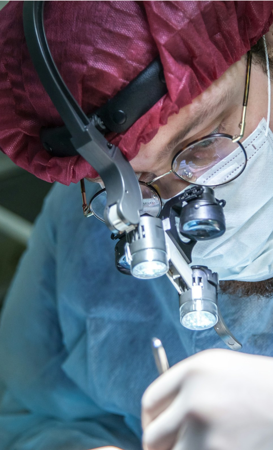 Medical professional wearing surgical loupes performing precise medical procedure