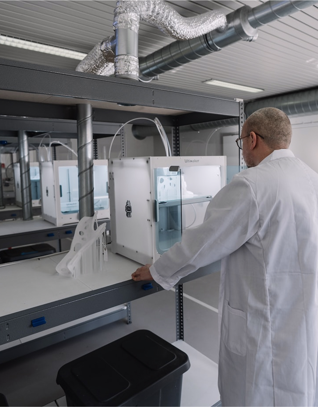 Scientist in lab coat working with 3D printer in research laboratory