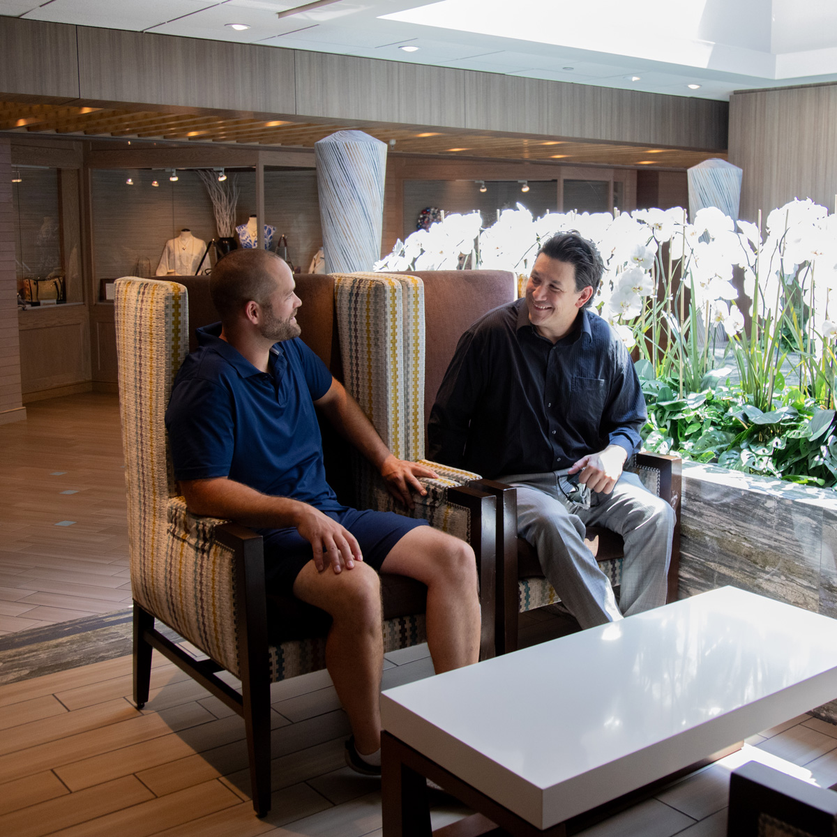 Two men sitting in chairs, talking and smiling in modern interior