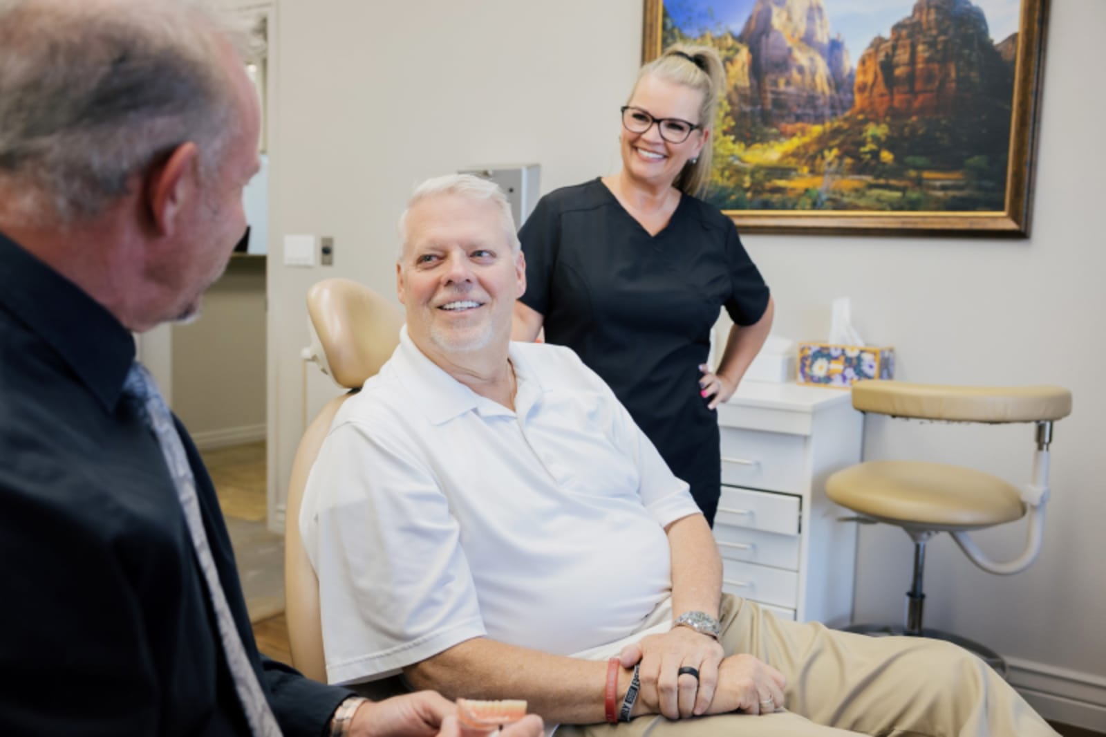 Dentist with patient examining model of teeth in treatment room