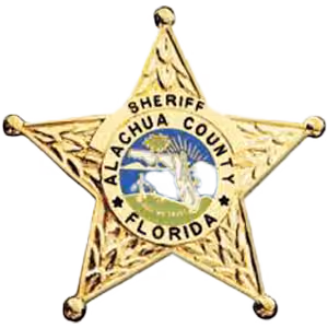 Gold star badge of Alachua County Sheriff, Florida, with a circular blue and white emblem in the center.