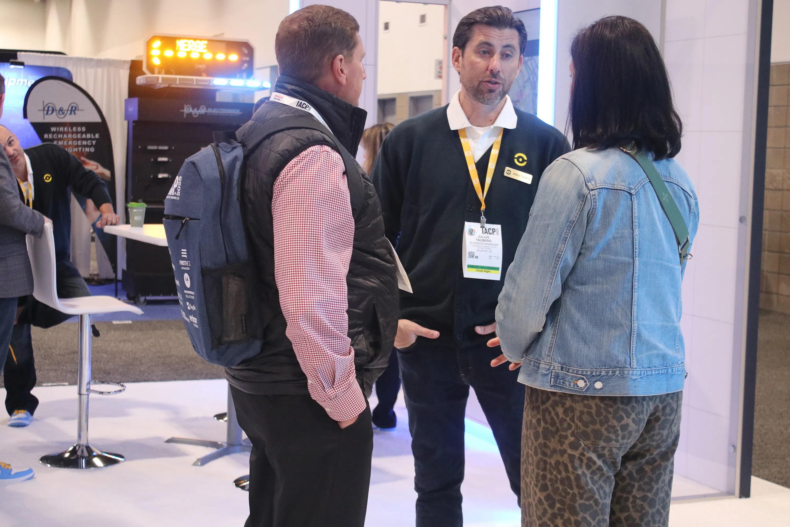 Three people engaged in conversation at an indoor event or conference.