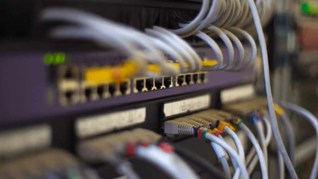 Close-up of network switch ports with multiple Ethernet cables plugged in, some color-coded.