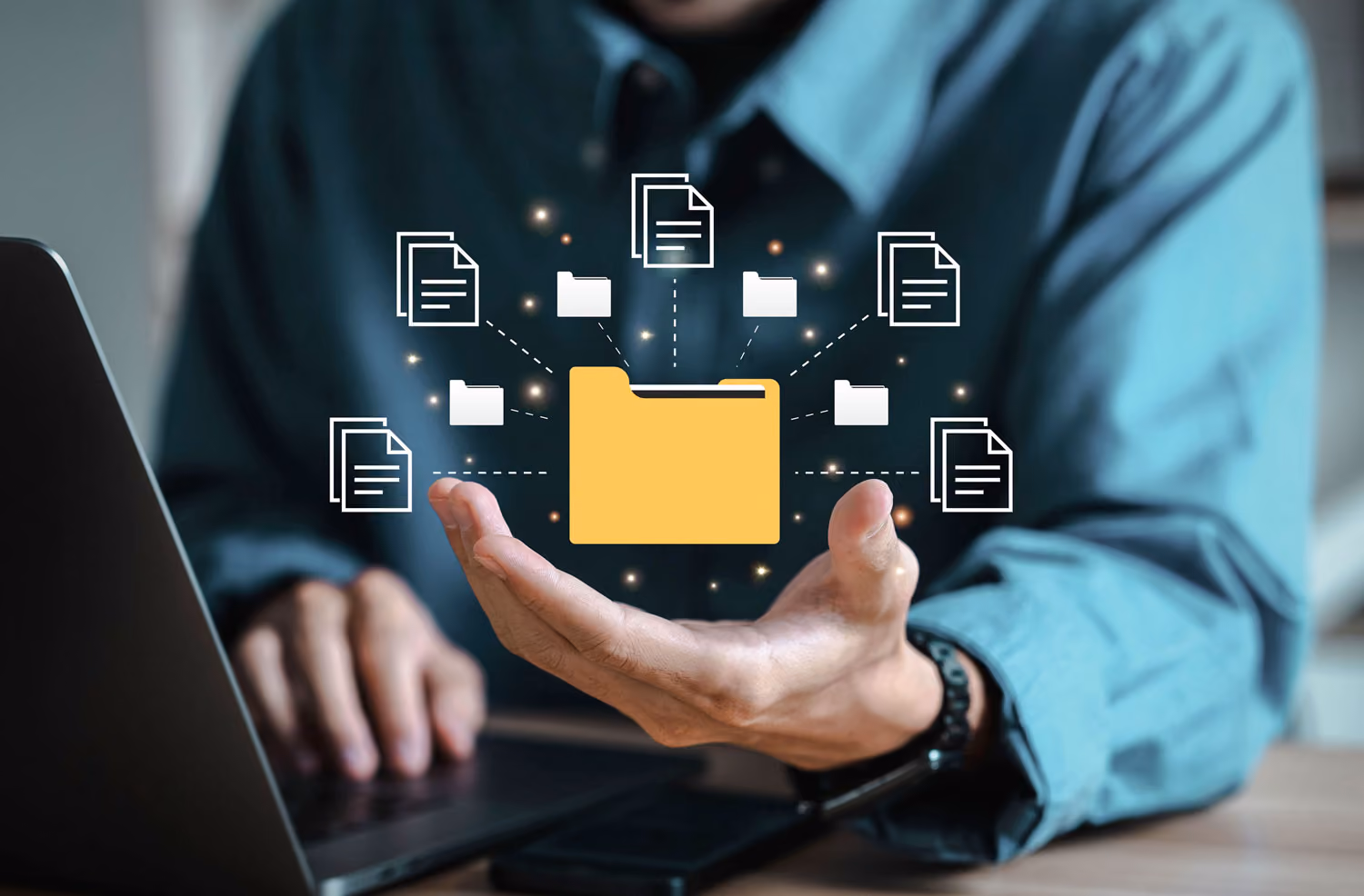 Person holding digital folder icon with files and folders above a laptop keyboard.