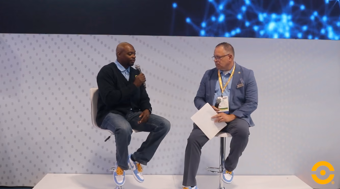Two men on a stage with microphones discussing police pillars and mobile technology, featuring the Coreforce logo in the corner.