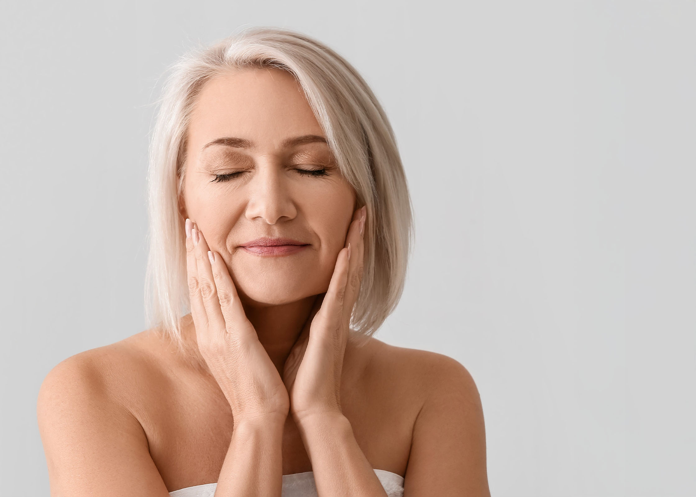 A woman smiling touching her face