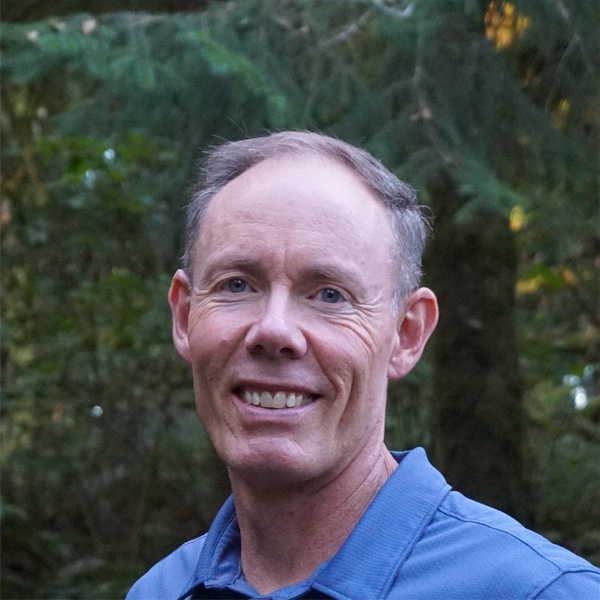 Greg Burnham smiling in an Oregon forest.