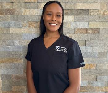 Professional picture of a woman wearing dark blue scrubs.
