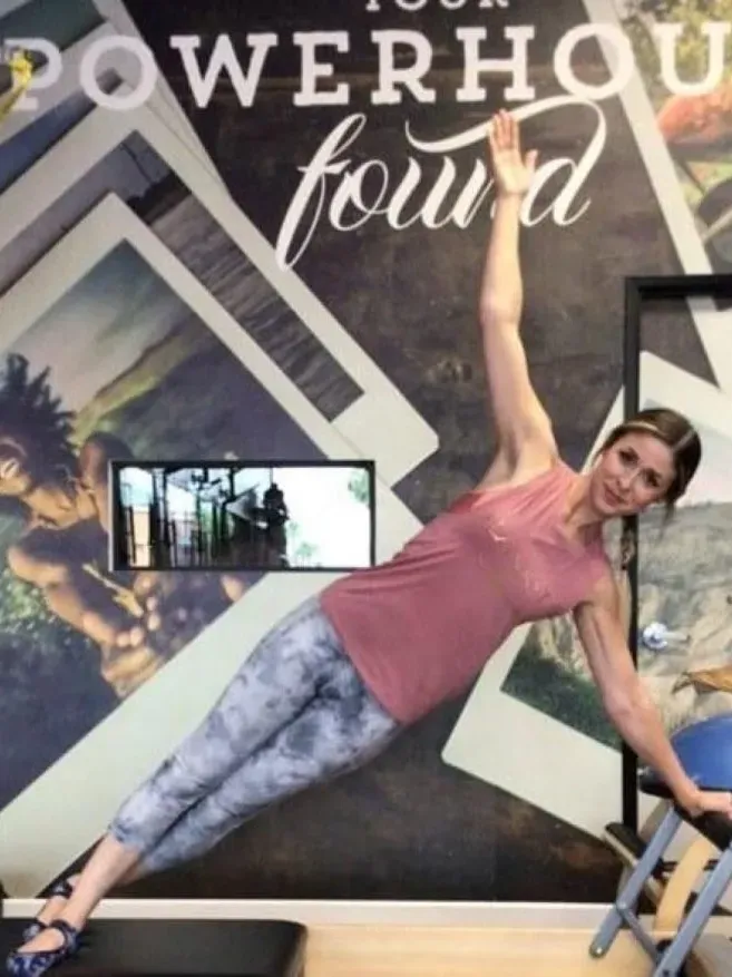 A woman in a pink tank top doing a handstand.