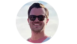 A man wearing sunglasses and a pink shirt.