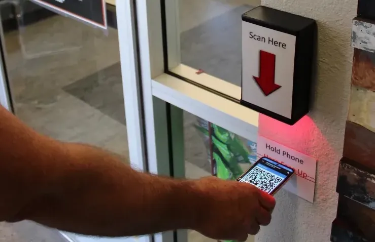 A person holding a cell phone in front of a scanner.