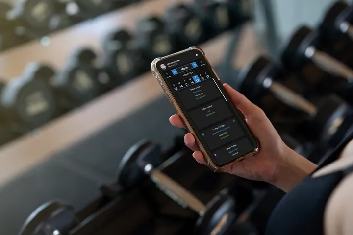 A person holding a cell phone with a screen displaying a workout routine.