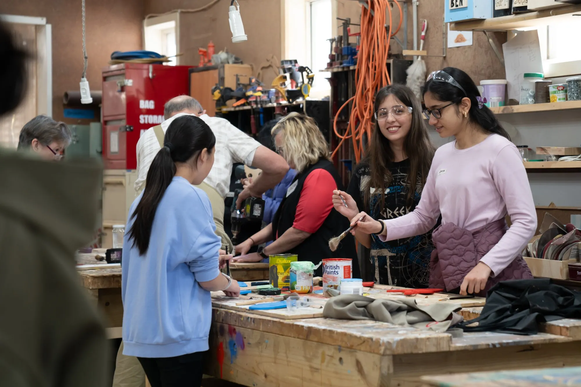 Group of people working on a woodworking and painting project in a workshop.