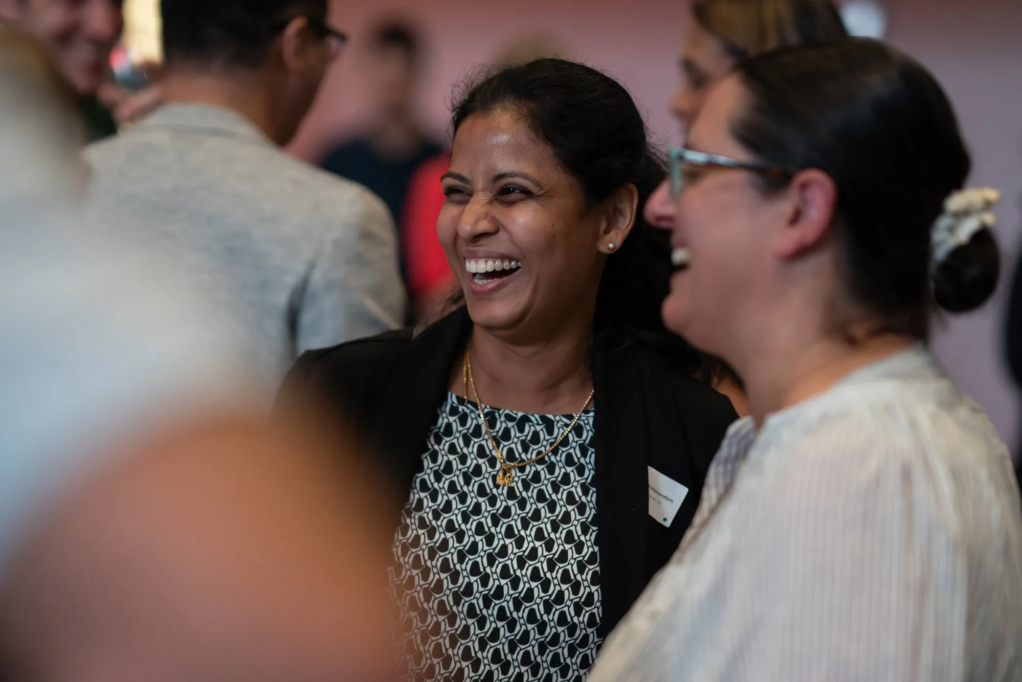 Two women laughing and enjoying a conversation at a social gathering.
