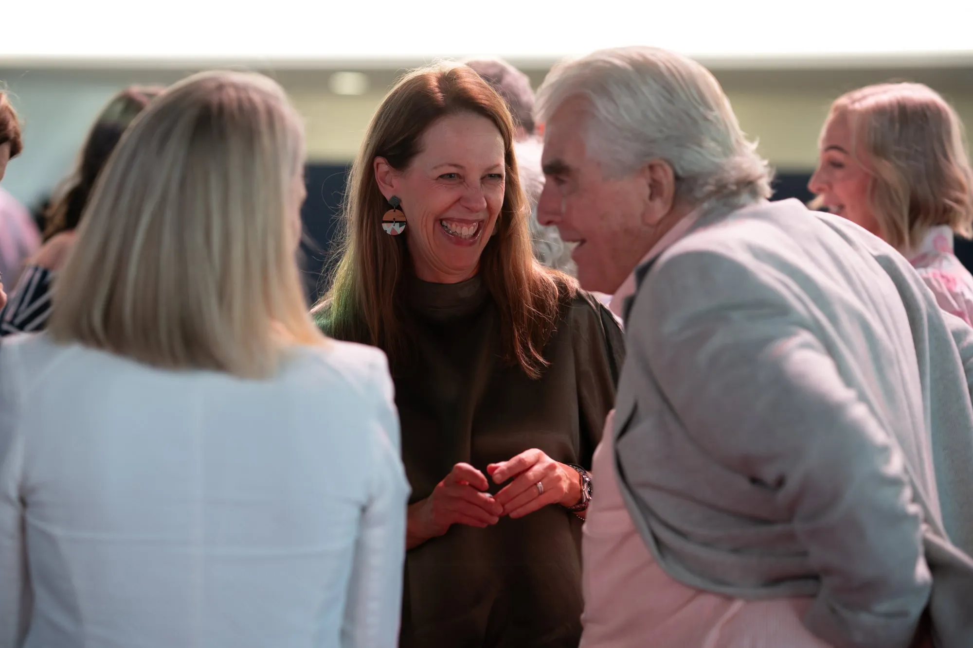 Group of people smiling and engaging in lively conversation at a social event.