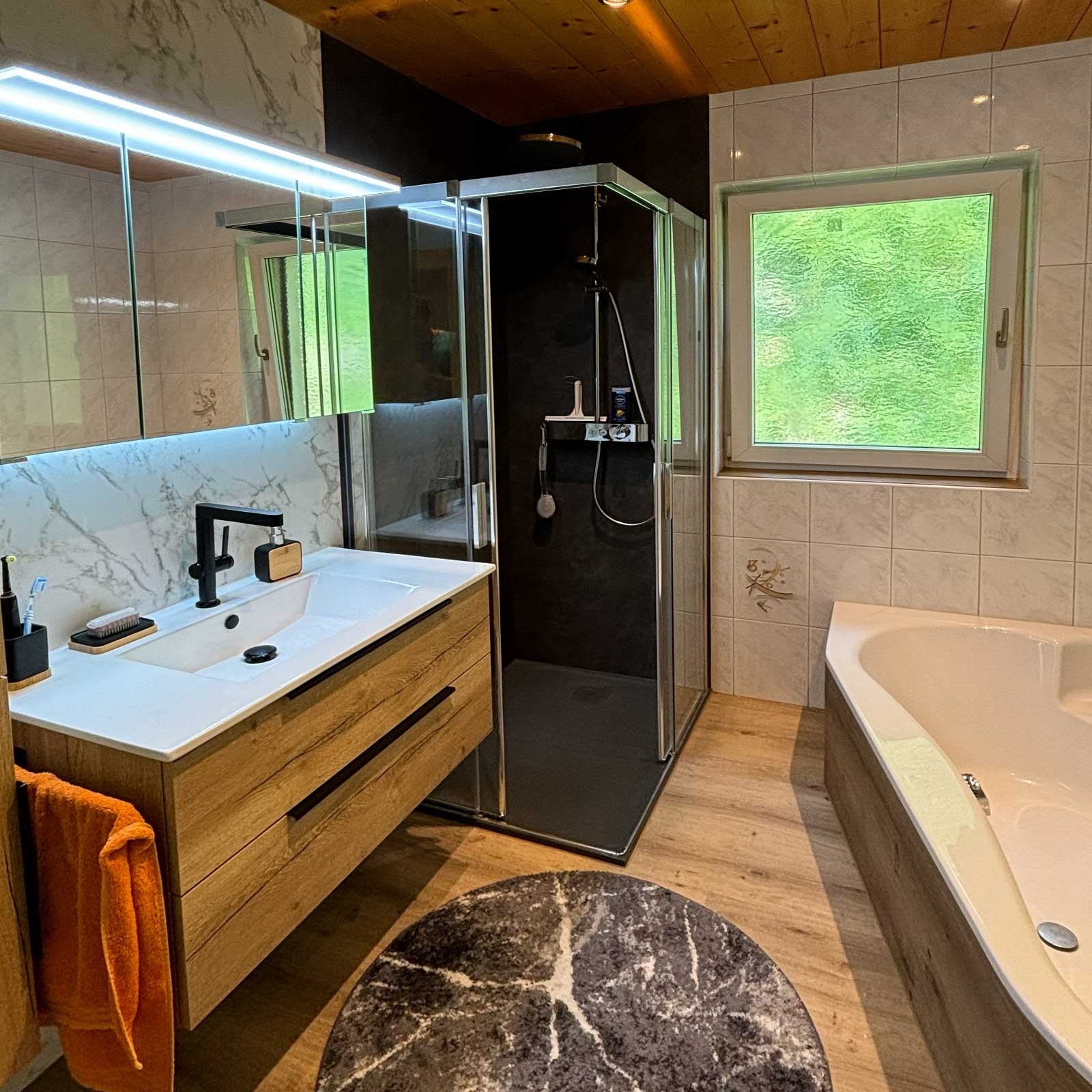 Badrenovierung Tirol – modernes Badezimmer mit Holzoptik und Badewanne nach Badsanierung