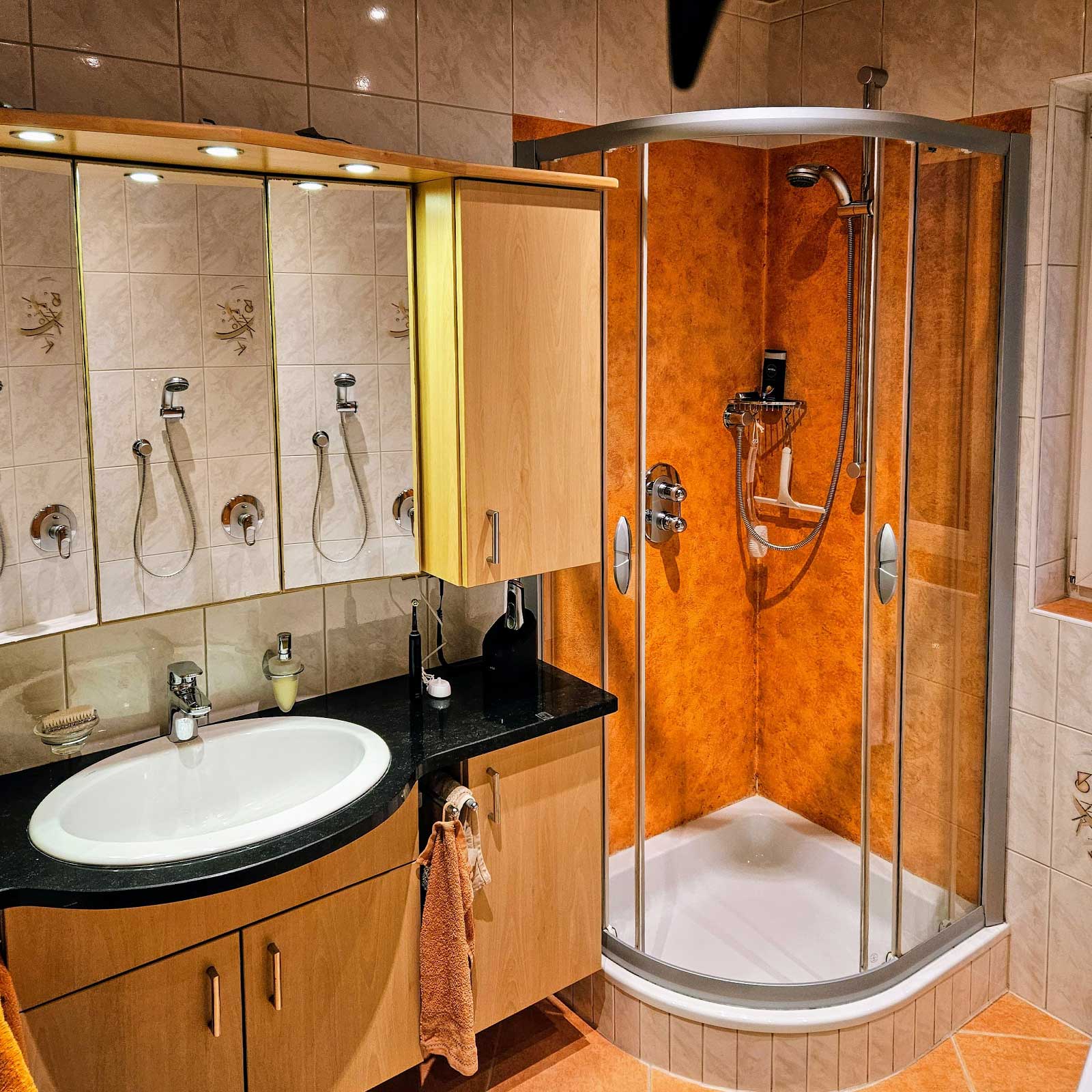 Modernes Neubad in warmer Holzoptik mit Glasdusche und zeitloser Sanitärkeramik.