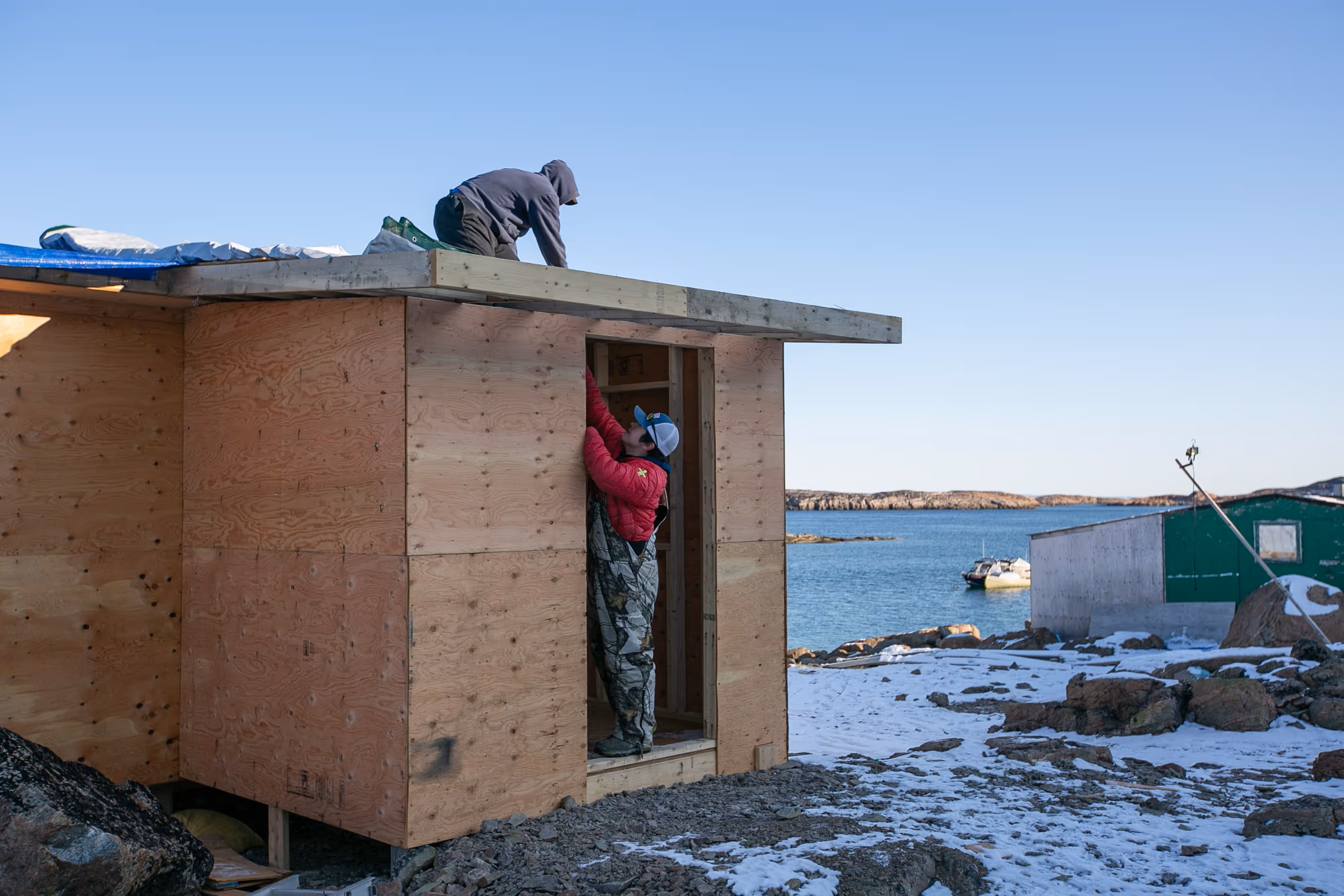 Two men do construction work on a small structure.