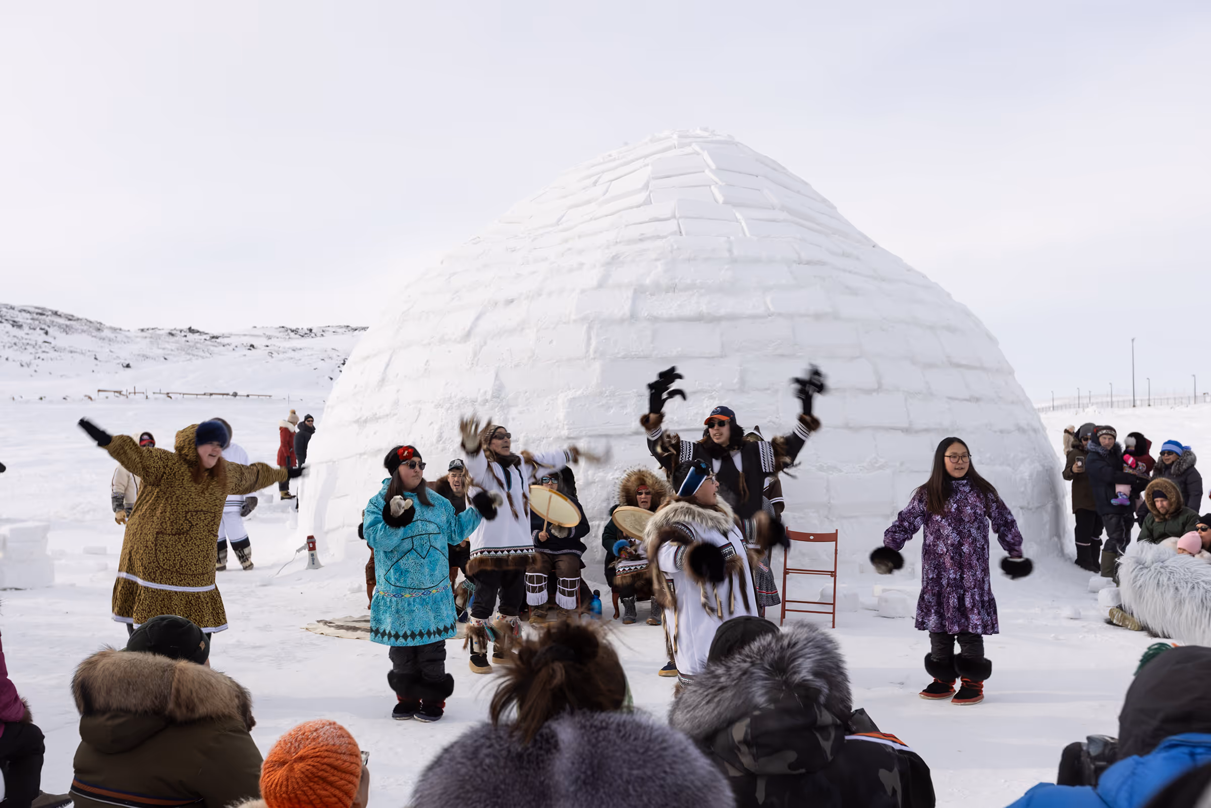 Group of people dancing outside of an igloo