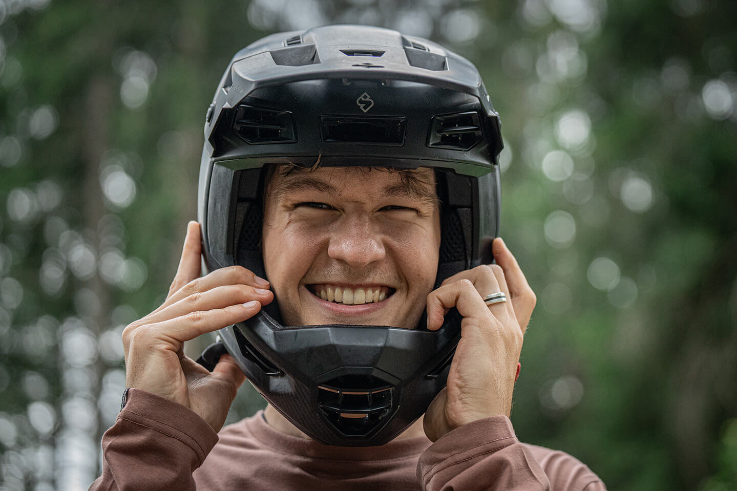 Man sieht ein Mann mit Fahrradhelm in die Kamera lachen