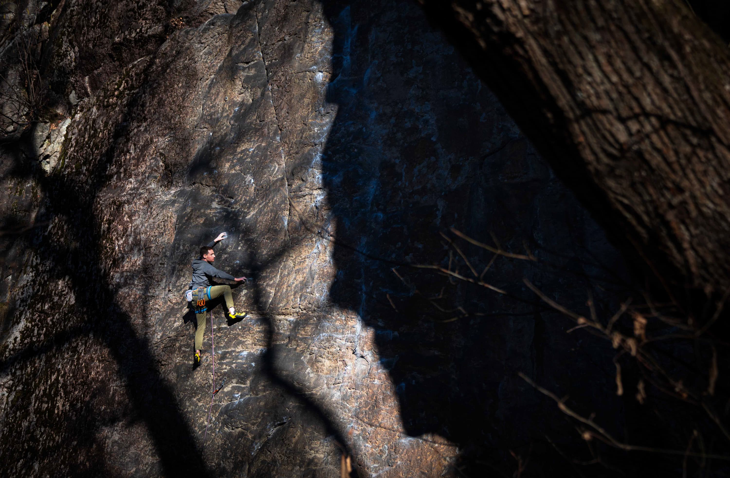 Das Bild zeigt einen Kletterer in einer Wand im Tessin. An der Wand sind schöne Schattenspiele zu sehen.