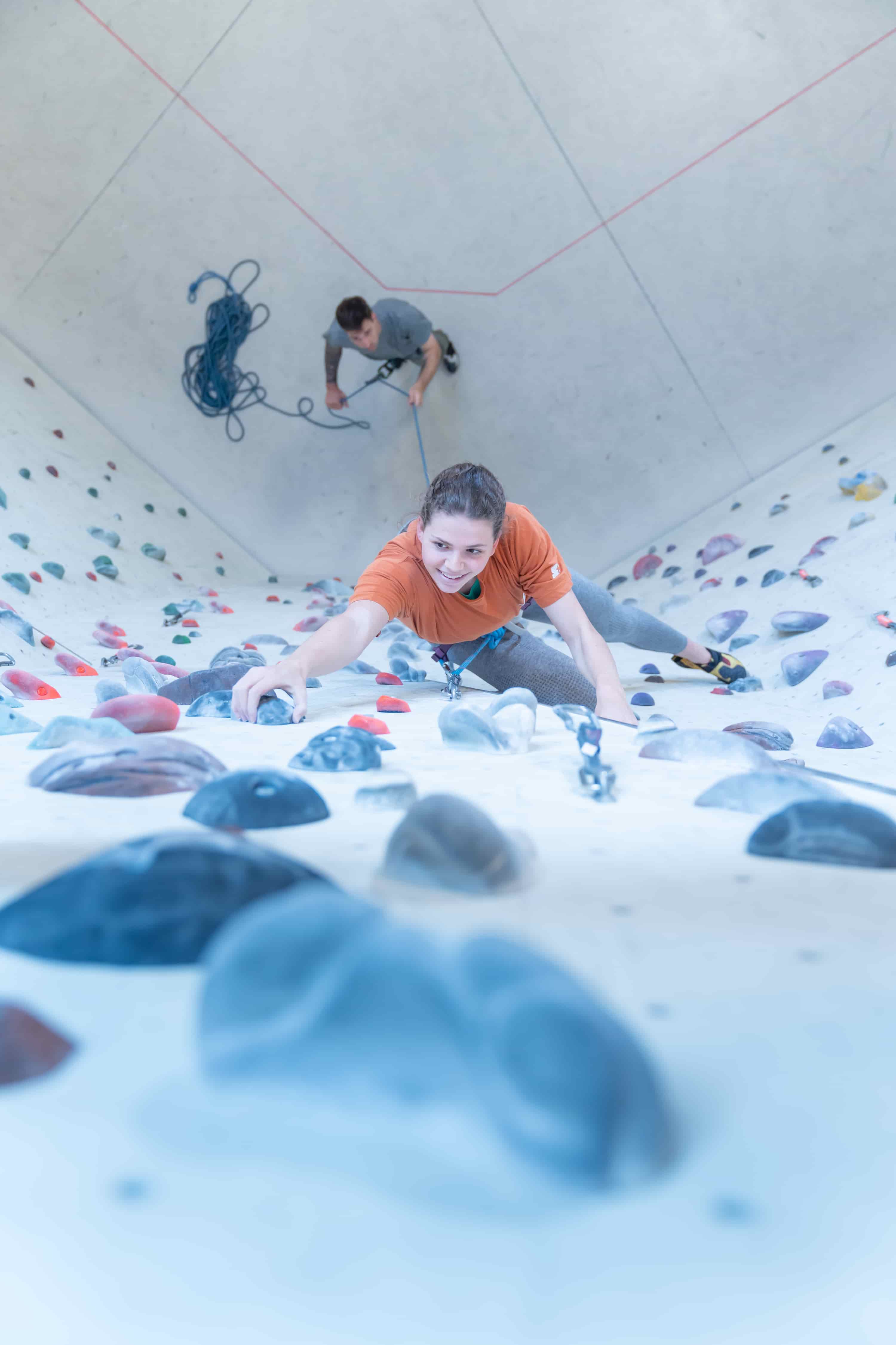 Es zeigt eine Kletterin welche im Vorstieg in der Halle klettert