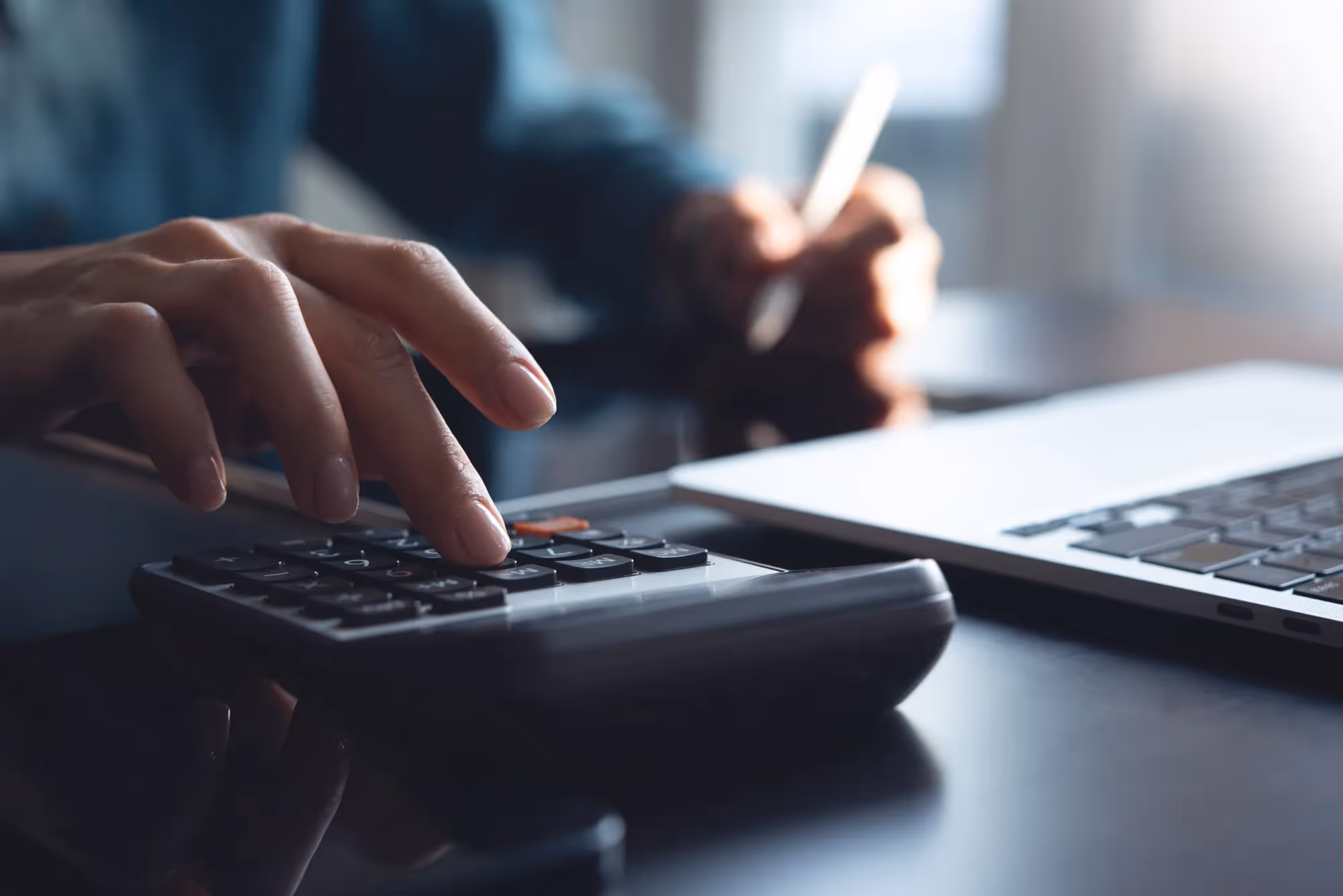 A person is using a calculator and a laptop.