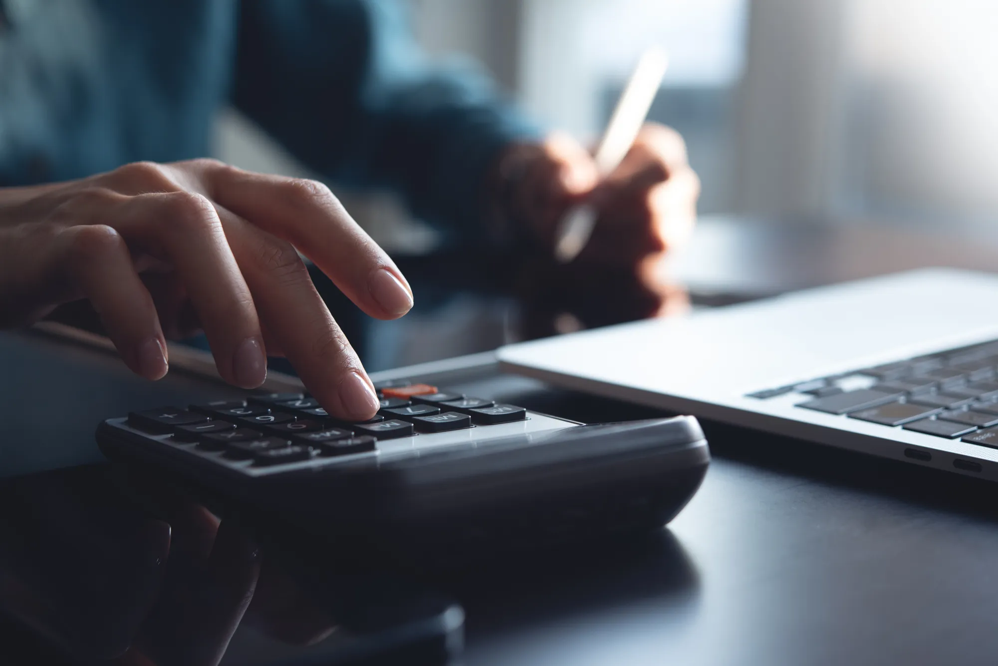 A person is using a calculator and a laptop.