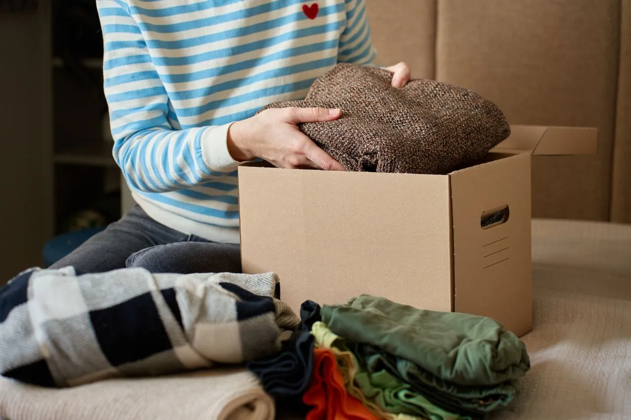 Folded clothes being packed into a moving box