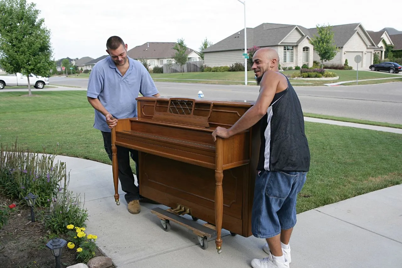 Movers wrapping a piano in protective blankets before moving it